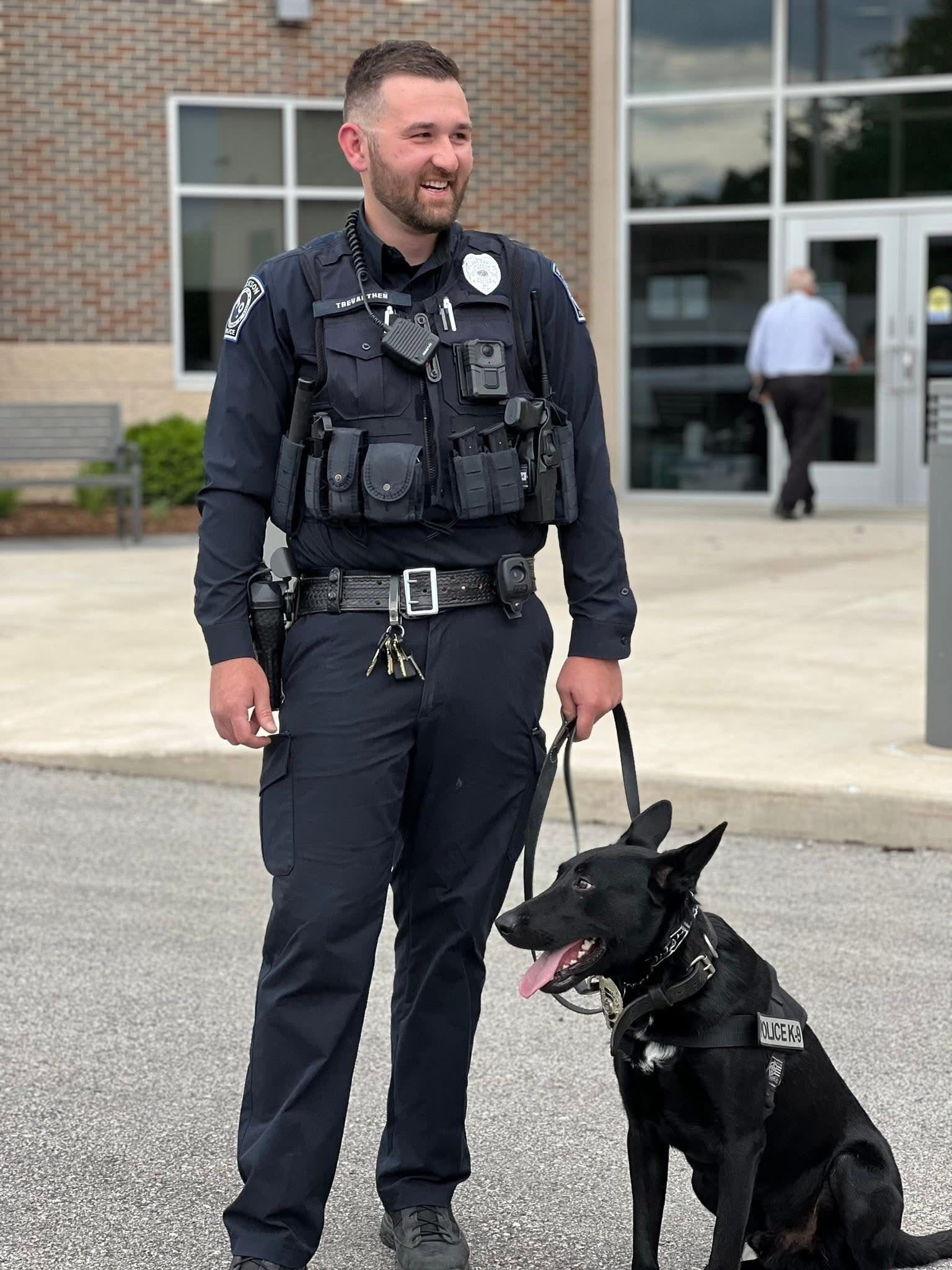 A photograph of a handsome police officer and handsome police dog at a ceremonial swearing in